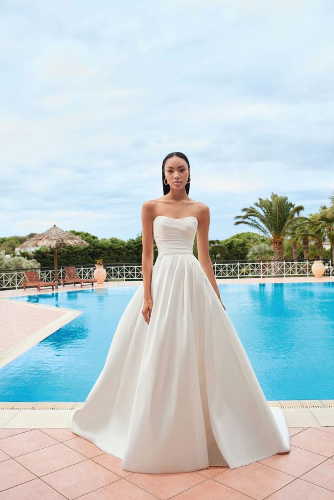 Strapless A-lijn trouwjurk stijl 200144 met hartvormige halslijn, zachte asymmetrische plooien, opvallende split en luxe satijn- of mikado-stof.