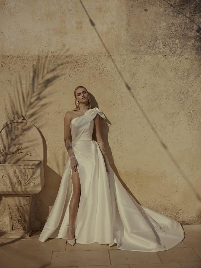 Trouwjurk Floriana met stretch mikado stof, one-shoulder halslijn en een elegante strik voor een moderne en couture-geïnspireerde uitstraling.