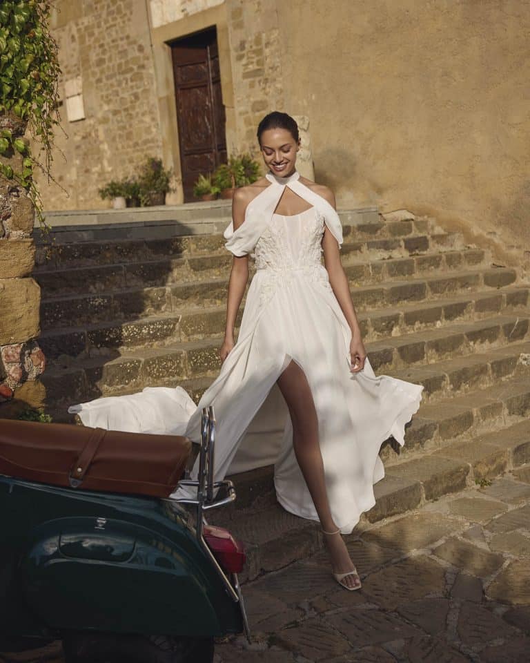 A-lijn trouwjurk Geneva met chiffon rok en split, pailletten kanten lijfje met 3D bloemen en bijpassende col-bolero.