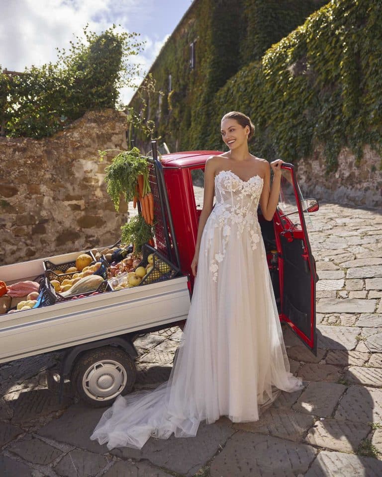 Strapless A-lijn trouwjurk Geralyn met sweetheart halslijn, gedrapeerd lijfje, kanten appliqués en sprankelende tule rok.