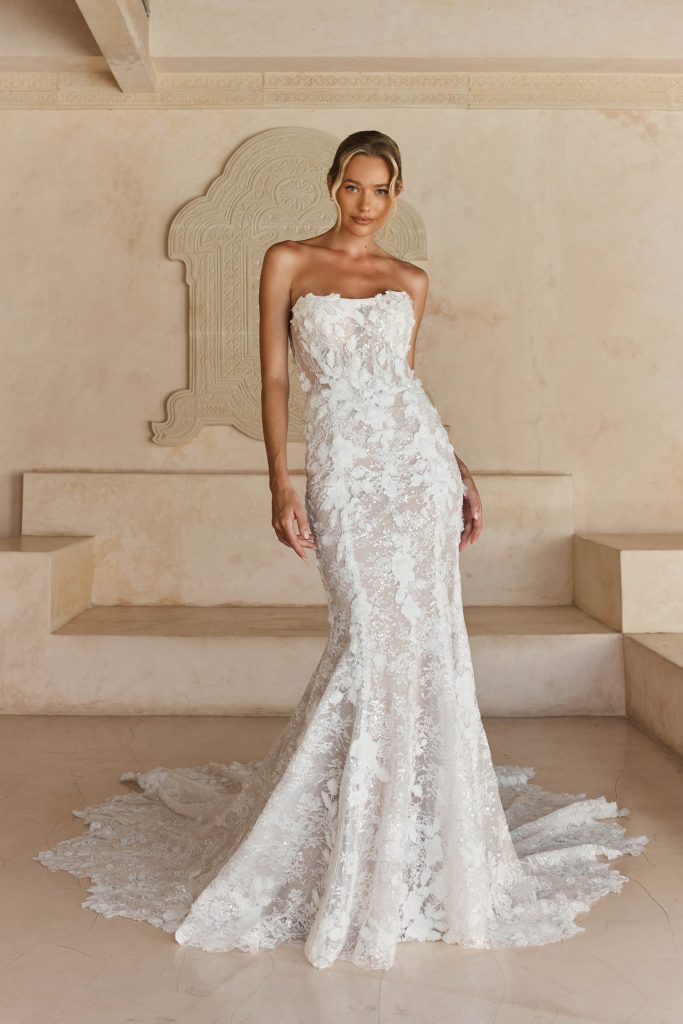 Fit-and-flare trouwjurk Leith van Madi Lane met shallow scoop halslijn, 3D kant, Basque taille, hoge rug en illusion lace sleep.