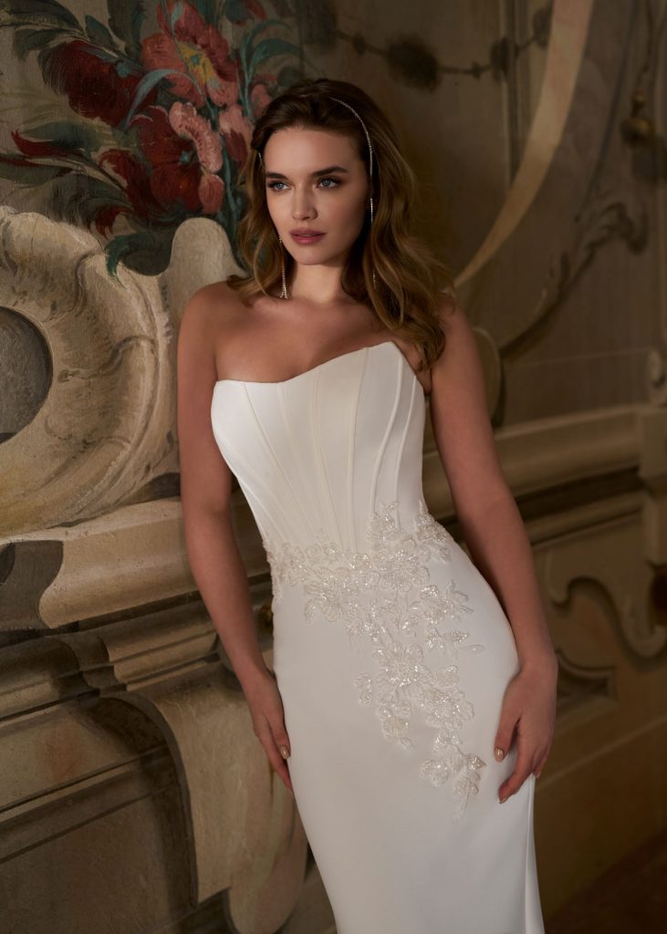 Fit-and-flare crêpe trouwjurk met strapless boothals, kralenkant op de rok, minimalistisch en romantisch design.