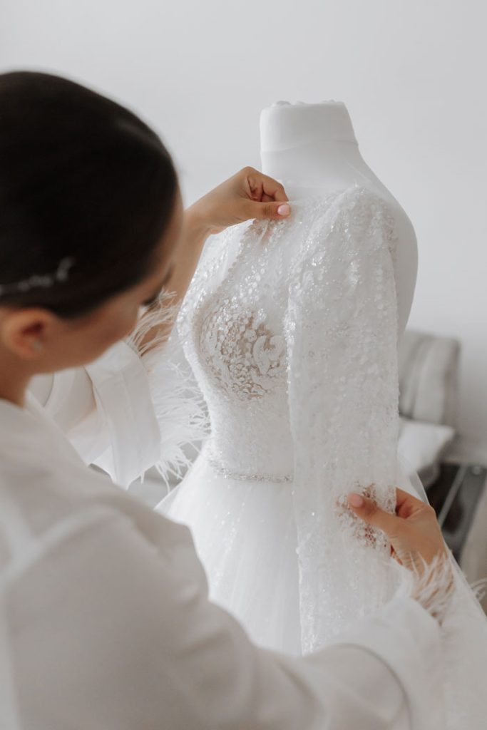 Vrouw zet trouwjurk op mannequin tijdens bruidsjurken passen bij Charmé Bridal