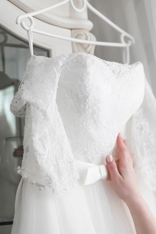 Hand voelt aan hoogwaardige stof van een bruidsjurk bij Charmé Bridal in de regio Utrecht